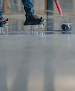 Epoxy installer using a roller to spread resin on floor