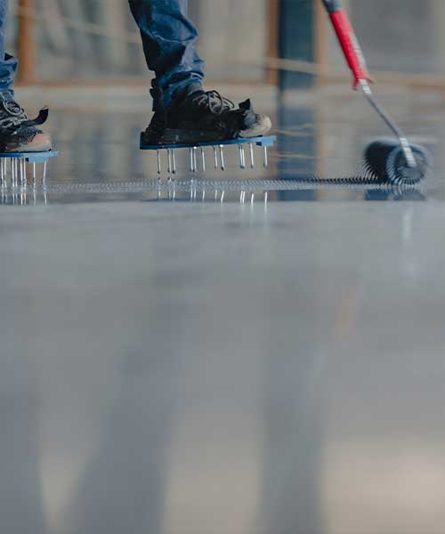 Epoxy installer using a roller to spread resin on floor