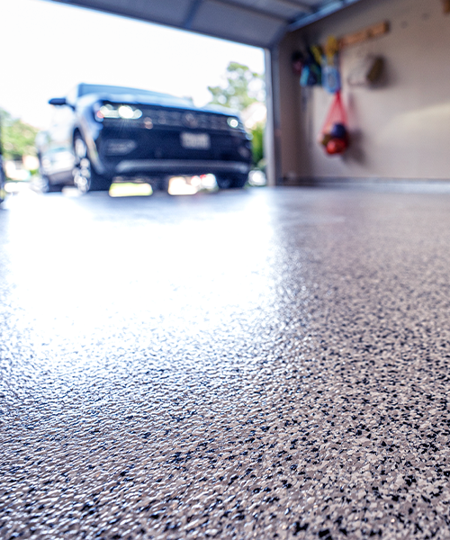 dark vehicle driving into garage with black and white epoxy floor